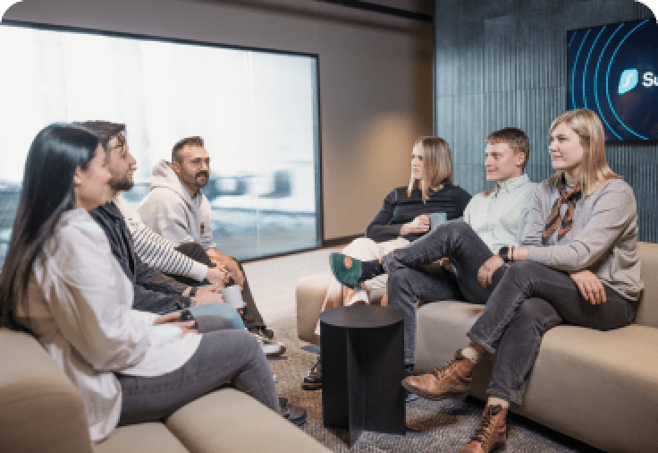 Six people sitting on two white couches facing one another.