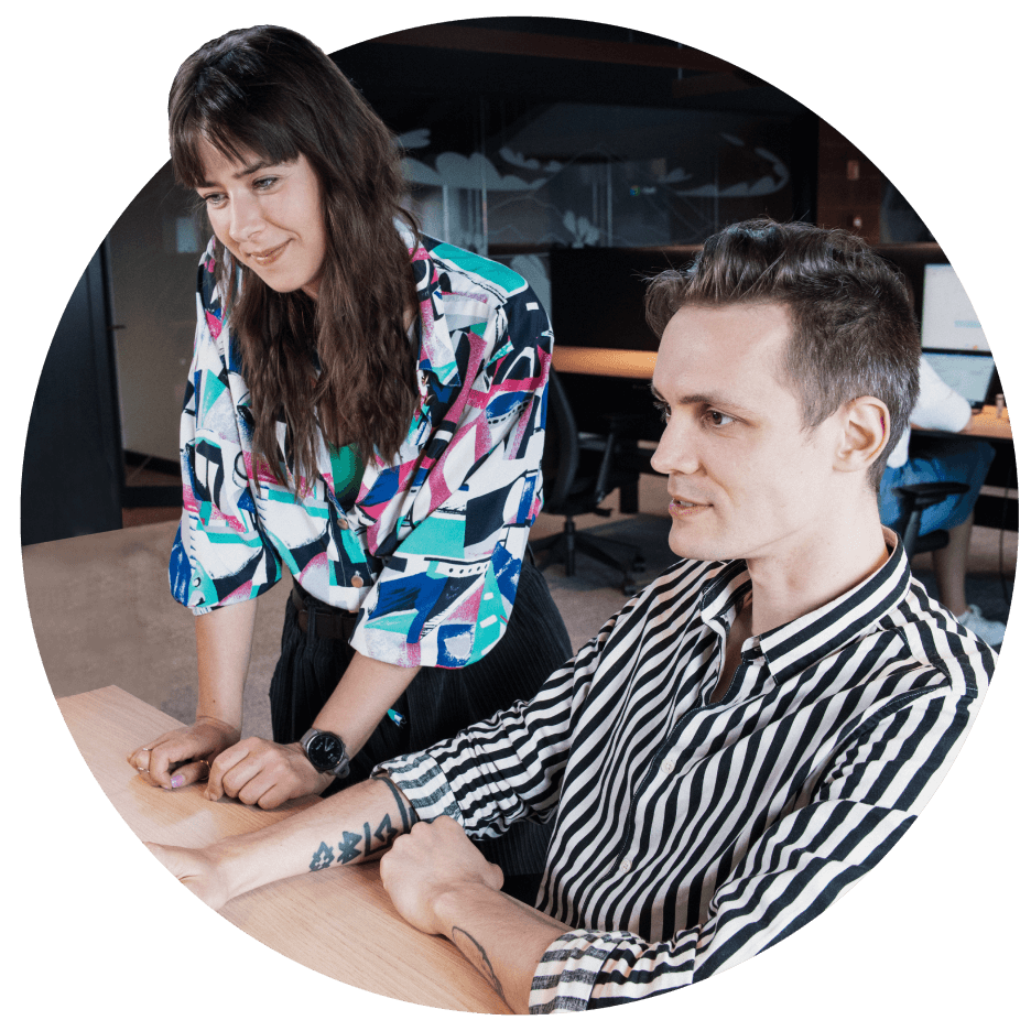 A smiling man and a woman looking at computer monitors.