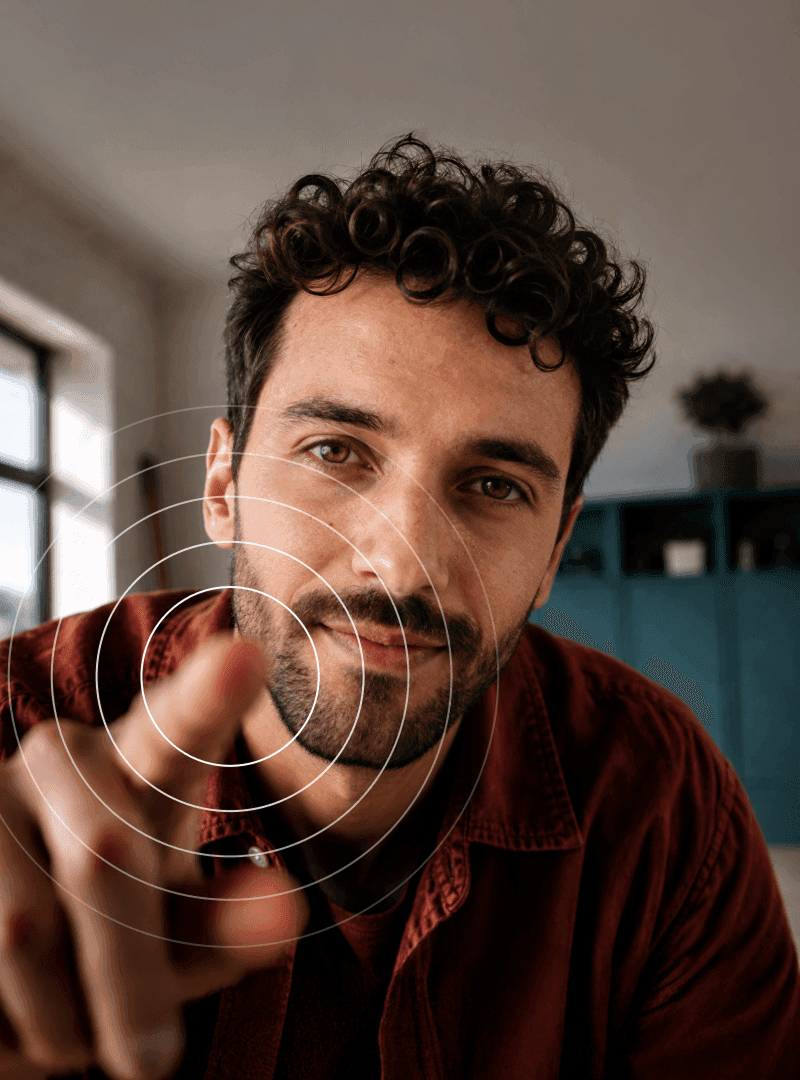 A man with curly hair and a beard reaching toward the camera with concentric white circles centered on his finger.