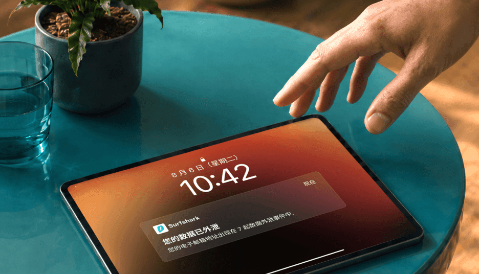 一只手伸向平板电脑,屏幕显示“您的数据已外泄”通知。
