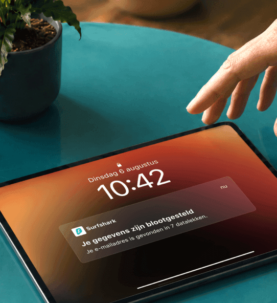 Een hand reikt naar een tablet met een melding die zegt: Je gegevens zijn gelekt.