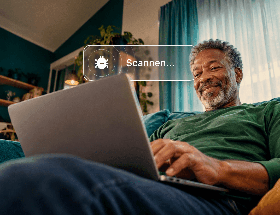 Een glimlachende man op een bank die een laptop gebruikt waarop een antivirusscan wordt uitgevoerd.