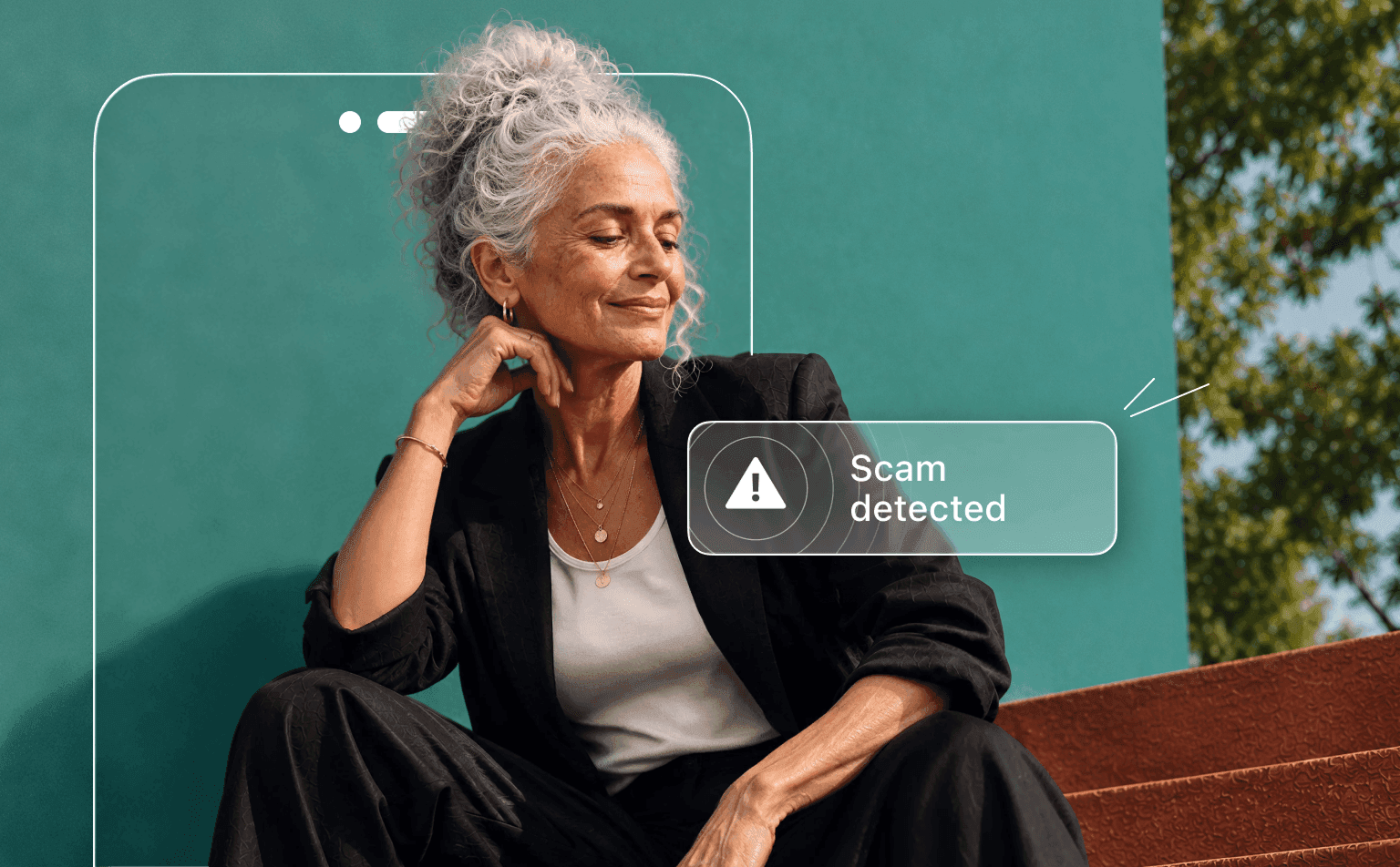 A woman with gray hair sits against a teal wall, partially obscured by a phone outline displaying a Scam detected alert.