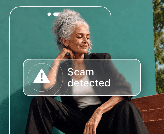 A woman with gray hair sits against a teal wall, partially obscured by a phone outline displaying a Scam detected alert.