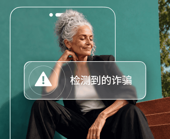 一位灰发女士坐在蓝绿色墙壁前,部分身体被手机轮廓遮挡,屏幕显示“检测到诈骗”警示。
